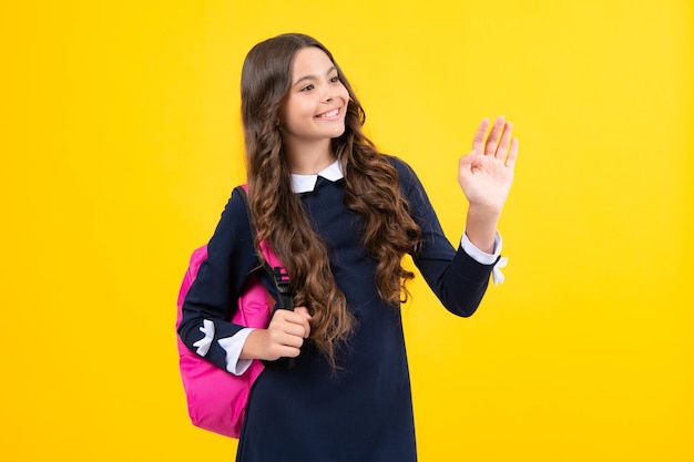 Schoolgirl in school uniform with school bag Teenage girl student on yellow isolated background Learning knowledge and children education concept
