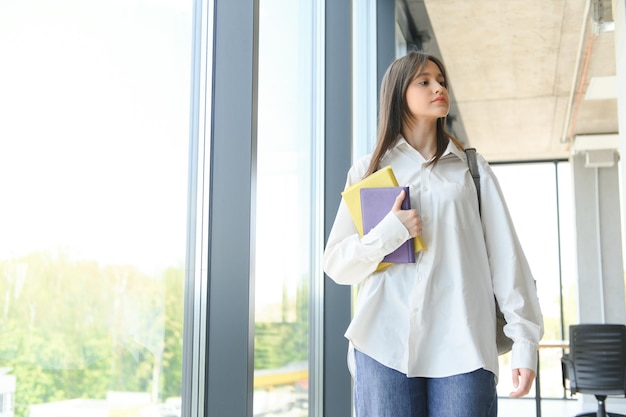 schoolgirl standing with books and backpack at school