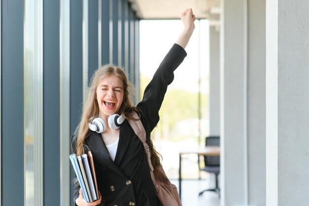 Foto studentessa in piedi con libri e zaino a scuola