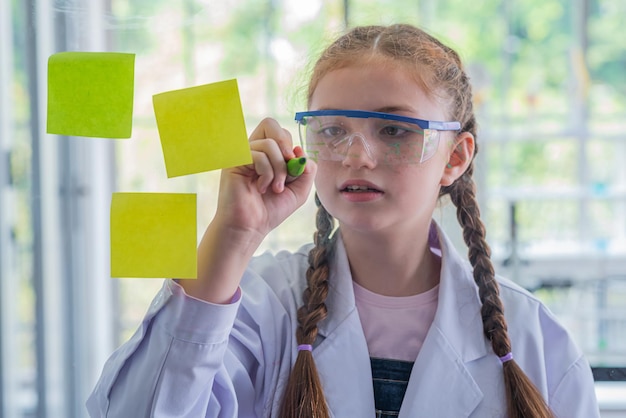 Foto la studentessa studia materie scientifiche e usa il pennarello per scrivere sul vetro a bordo