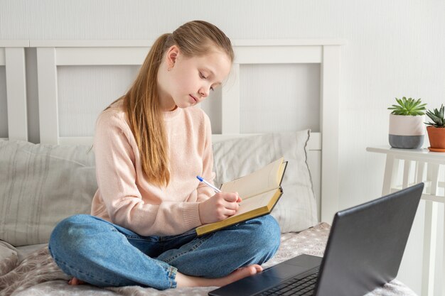 Schoolgirl studying at home using laptop. Online education, quarantine concept