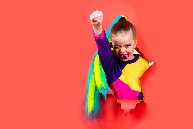 Photo schoolgirl superhero concept brave girl is breaking through color paper wall kid hand squeezed into