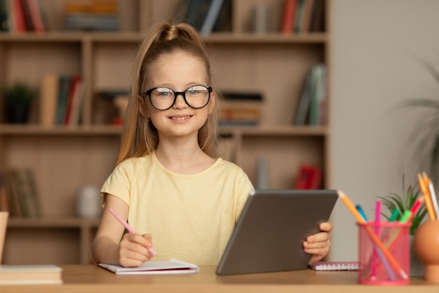 Schoolgirl Taking Notes Using Digital Tablet Posing Sitting Indoors