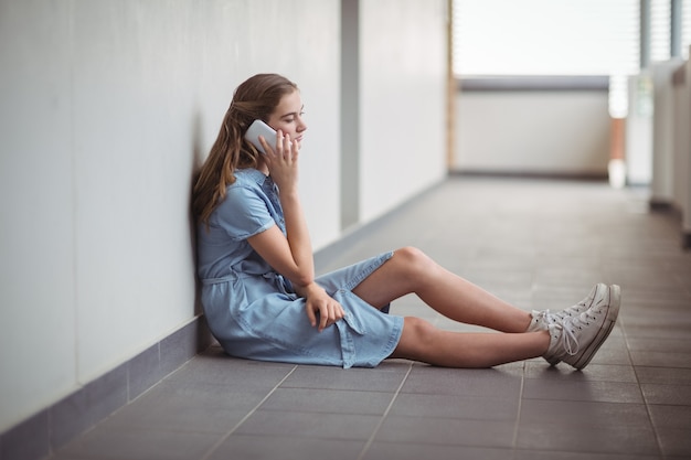 Schoolgirl talking on mobile phone in corridor