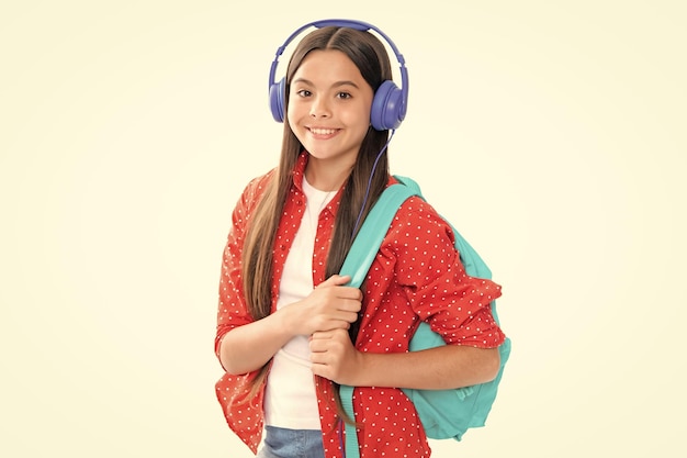 Schoolgirl teenage student girl in headphones on white isolated studio background School and music education concept Back to school Portrait of happy smiling teenage child girl