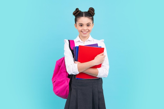 Schoolgirl teenage student girl hold book on blue isolated studio background School and education concept Back to school Happy teenager positive and smiling emotions of teen girl