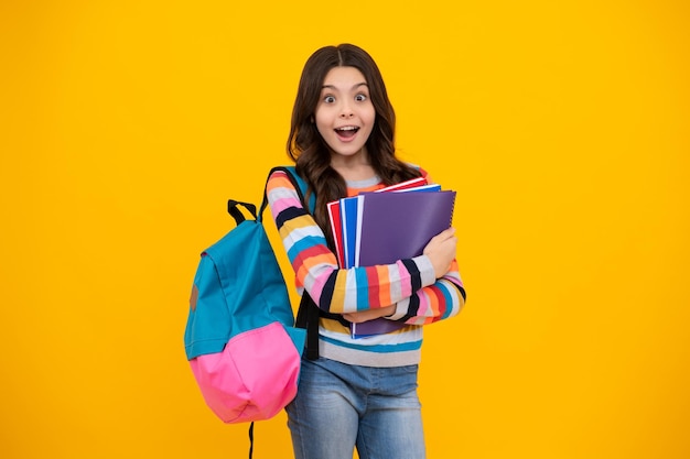 Schoolgirl teenage student girl hold book on yellow isolated studio background School and education concept Back to school Happy teenager positive and smiling emotions of teen girl