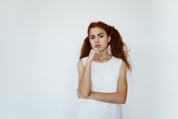 Schoolgirl thoughtfully put her hand to her chin on a light background