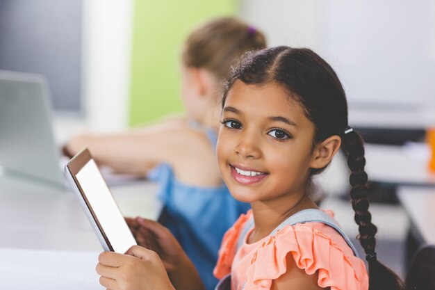 Schoolgirl using digital tablet in classroom