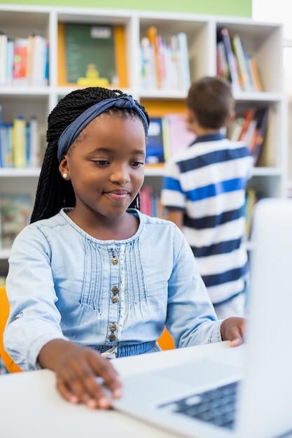 Schoolgirl using laptop in library