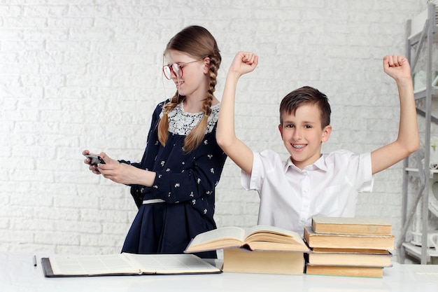 Schoolgirl using smartphone while schoolboy reading book