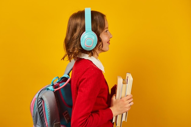バックパックのヘッドフォンと本を手に学校に戻る女子高生