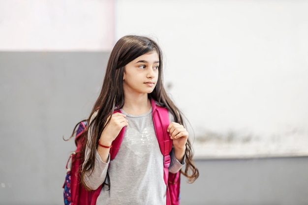 A schoolgirl with big backpack entering the class