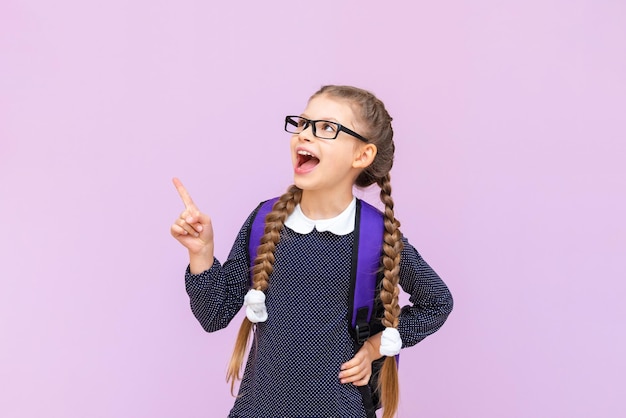 A schoolgirl with a briefcase and glasses on an isolated purple background primary school education at school courses for preparing children for school