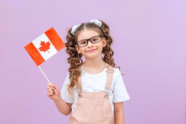 Una studentessa con una bandiera canadese e occhiali su uno sfondo isolato. ottenere un'istruzione in una scuola canadese.