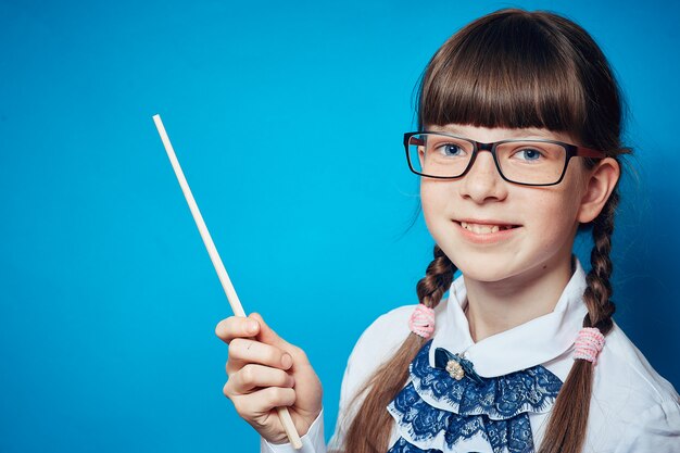 Schoolgirl with glasses and a pointer on a blue background