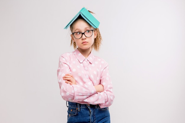 schoolgirl with glasses with a book on the head