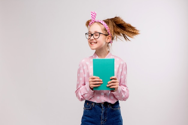 schoolgirl with glasses with a book smiling