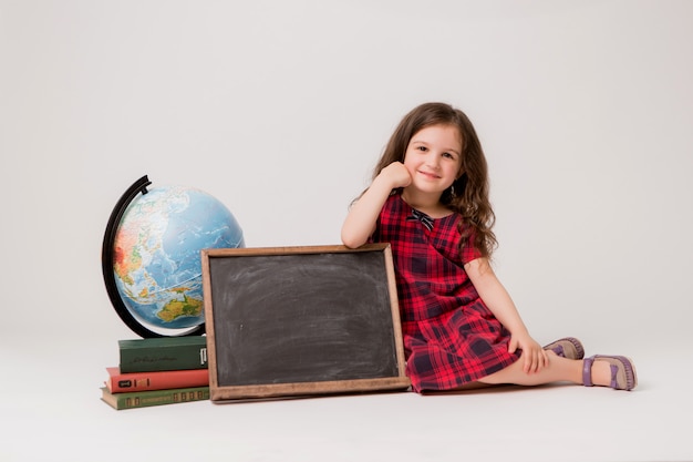 schoolgirl with globe, books and blank drawing Board on white background