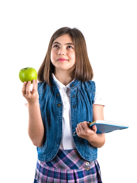 Schoolgirl with notebook and apple on white