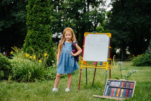 A schoolgirl writes lessons on a blackboard and is engaged in outdoor training. Back to school, learning during the pandemic.