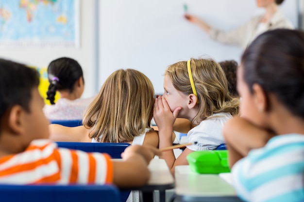 Schoolgirls gossiping in classroom