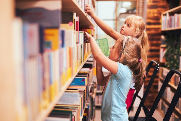 Photo schoolgirls looking for books in school library students choosing set books back to school