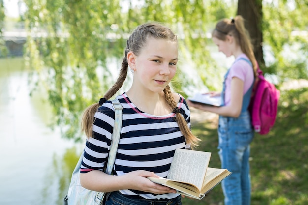 Schoolgirls reading books in nature