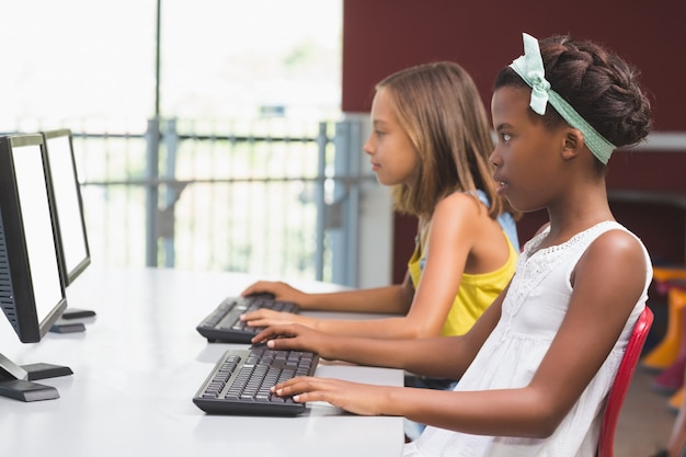 Schoolgirls using computer in classroom