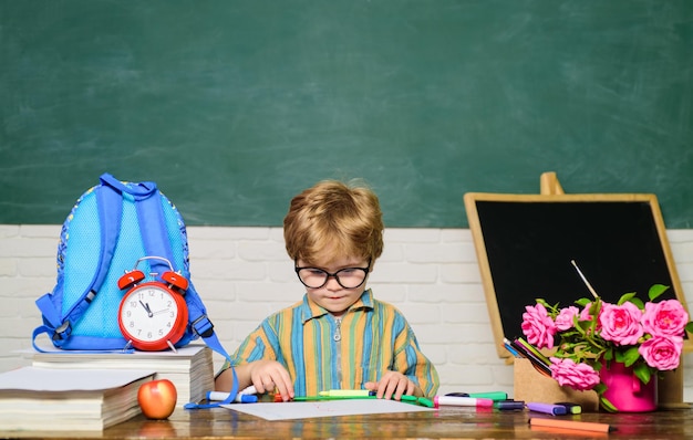 Schooljongen aan bureau basisschool student tekenen op werkplek kind leren in de klas kleine leerling