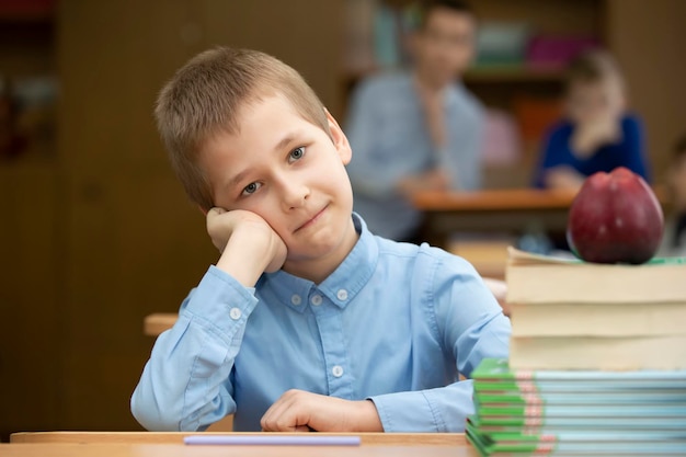 Schooljongen aan de balie Jongen in de klas met boeken en een appel Middelbare school Terug naar school