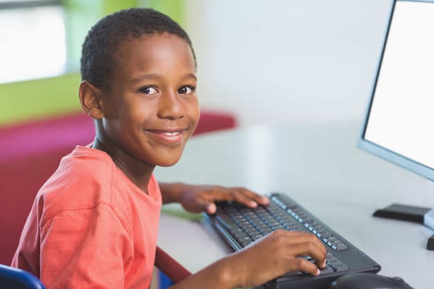 Schooljongen die computer in klaslokaal met behulp van