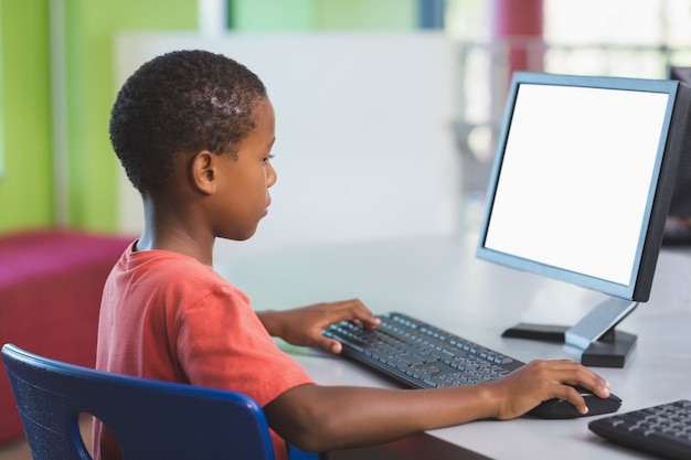 Schooljongen die computer in klaslokaal met behulp van