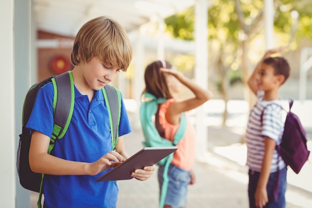 Schooljongen die digitale tablet in schoolgang gebruiken