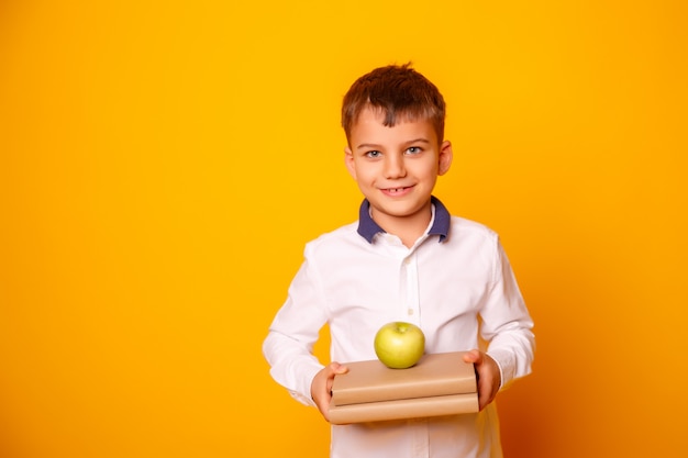 Schooljongen die met glazen boeken en een appel houdt