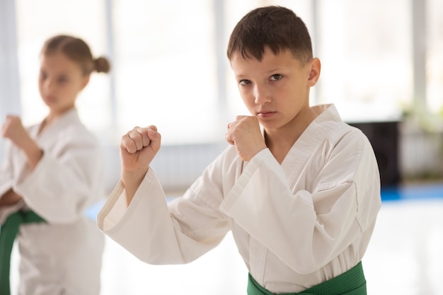 Schooljongen en aikido. Donkerharige schooljongen in witte kimono die zich goed voelt tijdens het beoefenen van aikido