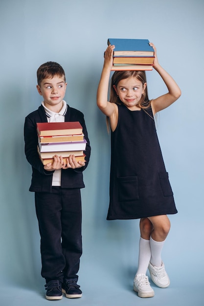 Schooljongen en schoolmeisje dragen uniform en houden boeken vast