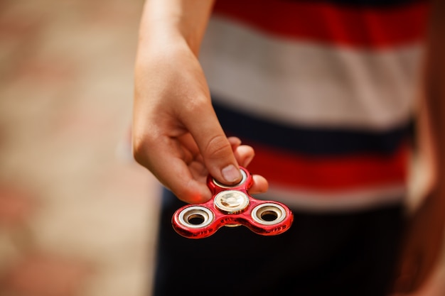 Schooljongen houdt een spinner fidget in zijn handen. Trendy en populair speelgoed voor kinderen en volwassenen.