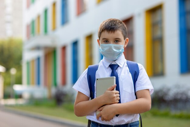 Schooljongen in een wit overhemd, blauwe stropdas en een rugzak