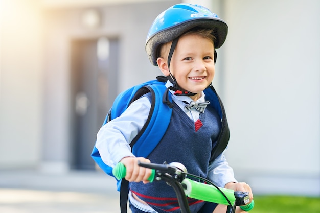 schooljongen in veiligheidshelm fiets met rugzak