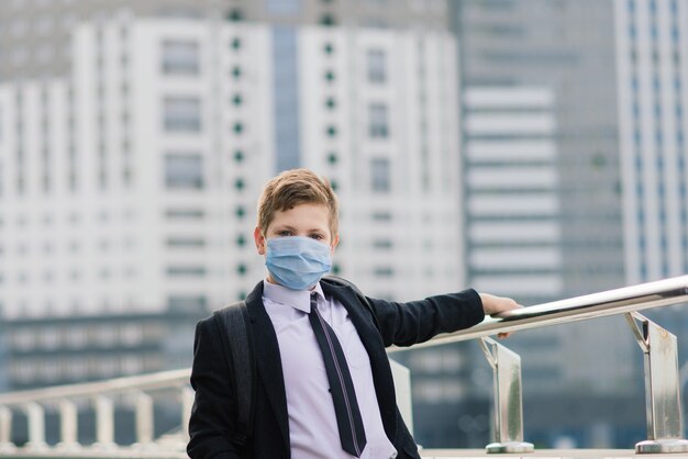 Schooljongen loopt de school uit met een beschermend masker in de stad