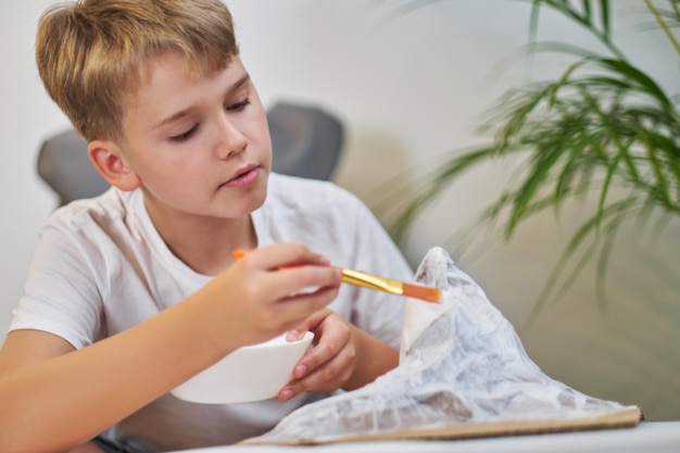 Schooljongen maakt creatief project in de vorm van een berg van papier-maché