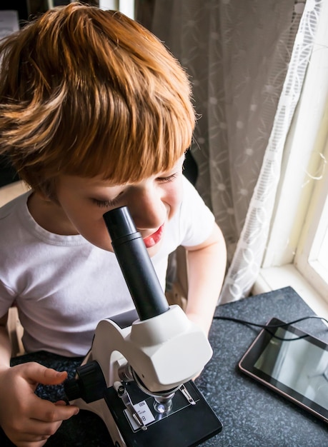 Schooljongen met behulp van microscoop, onderzoek naar bril met laboratoriummaterialen, science lab kids concept