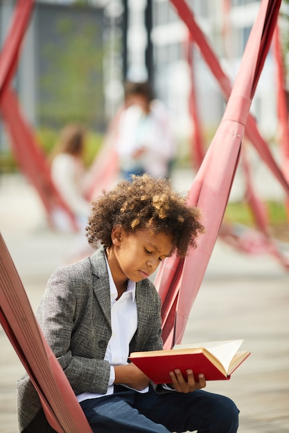 Schooljongen met boek buitenshuis