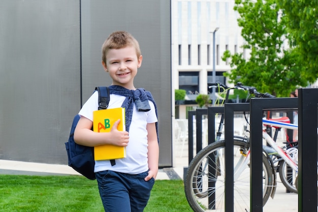 Schooljongen met een boek in zijn hand op straat op weg naar school. terug naar school.