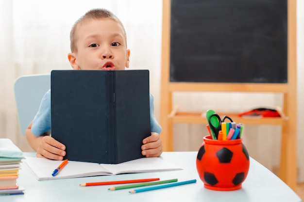 Schooljongen om thuis te zitten klaslokaal liggend bureau gevuld met boeken trainingsmateriaal schoolkind slapen lui verveeld