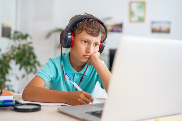 Schooljongen op videoconferentie met een leraar op laptop