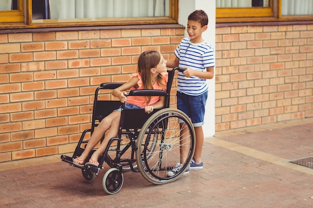 Schooljongen praten met een meisje op rolstoel