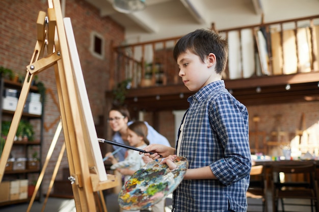 Schooljongen schilderen op ezel