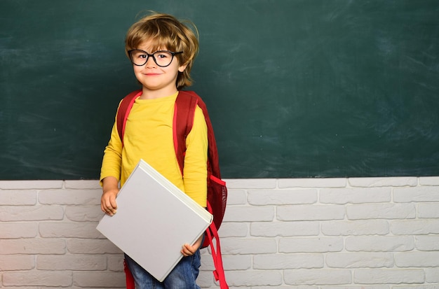 Foto schooljongen voor kinderen van de basisschool op het schoolplein, blije stemming die breed lacht op school